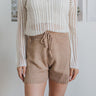 Front/close up view of model wearing the Everyday Dreams Shorts which features taupe knit fabric and elastic waistband with drawstring ties.