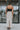 Full body back view of model wearing the Trend Setter Cargo Midi Skirt that has taupe light weight fabric, side cargo pockets, an elastic waist with a black drawstring tie, two upper pockets and a back slit