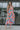 Full body front view of model wearing the Pacific Coast Floral Midi Dress that has purple, orange, pink, green, blue and cream fabric, floral and palm leaf print, and adjustable straps.