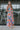 Full body side view of model wearing the Pacific Coast Floral Midi Dress that has purple, orange, pink, green, blue and cream fabric, floral and palm leaf print, and adjustable straps.