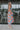 Full body side view of model wearing the Pacific Coast Floral Midi Dress that has purple, orange, pink, green, blue and cream fabric, floral and palm leaf print, and adjustable straps.