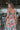 Back view of model wearing the Pacific Coast Floral Midi Dress that has purple, orange, pink, green, blue and cream fabric, floral and palm leaf print, and adjustable straps.