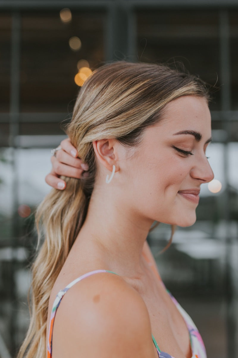 Side view of model wearing the Summer Loving Earrings in Ivory which features open, small hoops with cream acrylic.