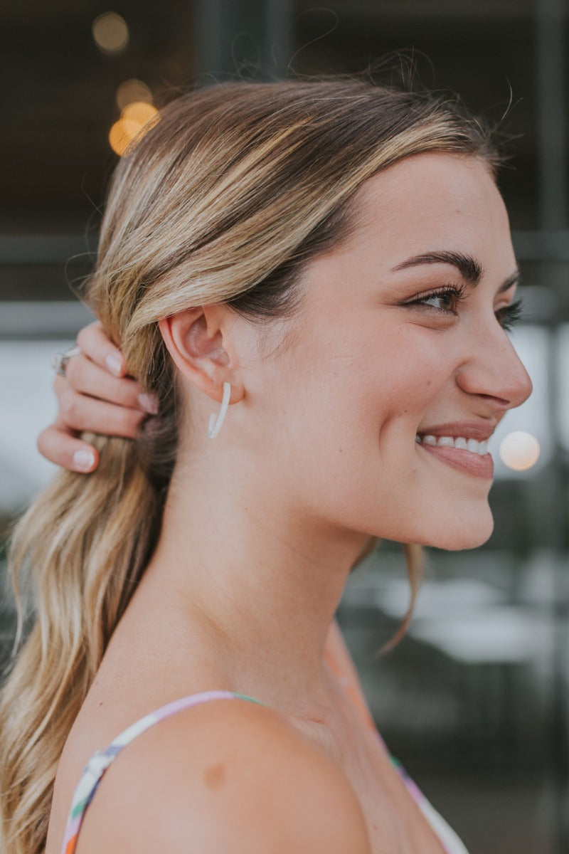 Side view of model wearing the Summer Loving Earrings in Ivory which features open, small hoops with cream acrylic.