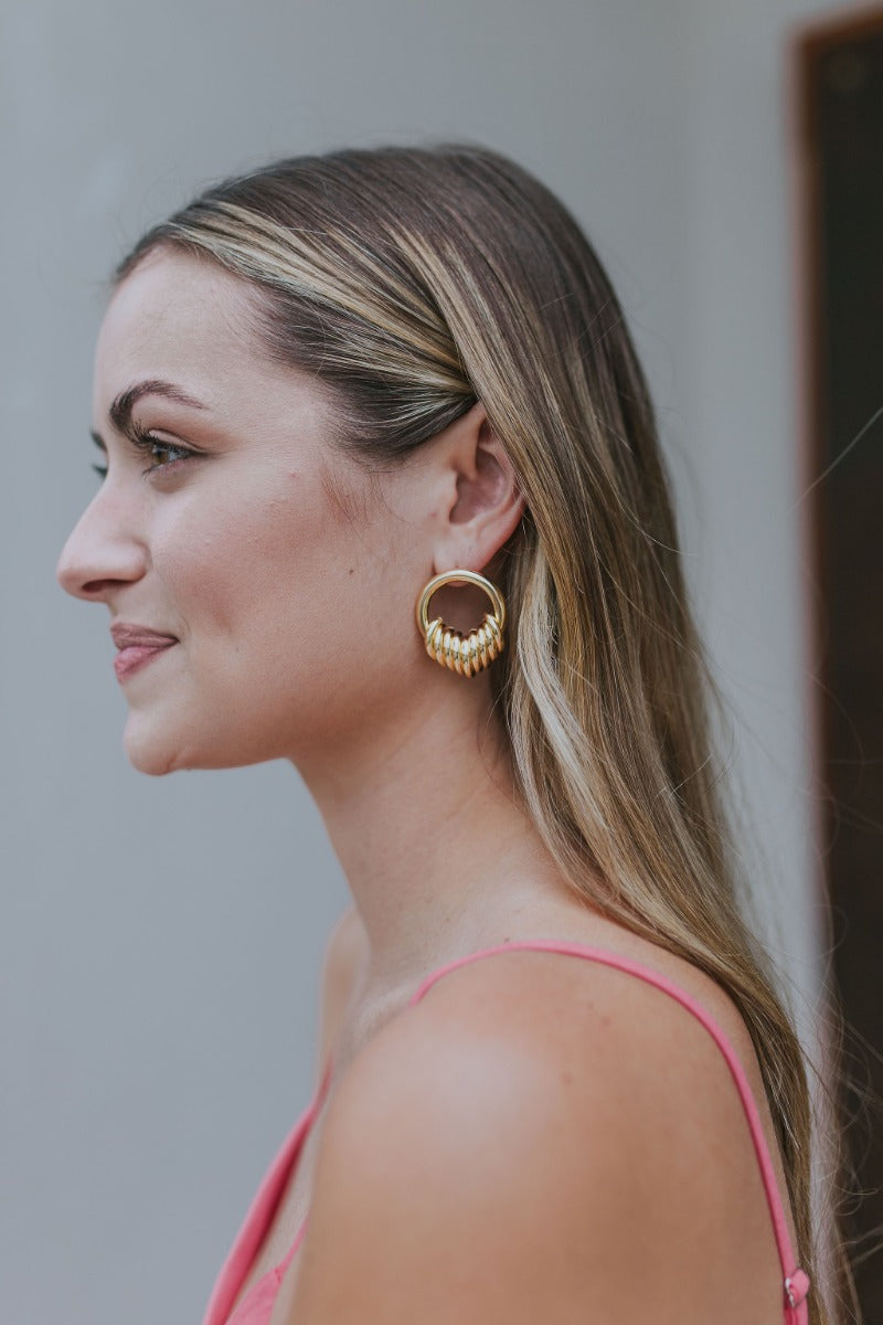 Side view of model wearing the With You Earrings which features gold closed circles with monochromatic hooks design.