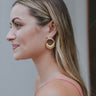 Side view of model wearing the With You Earrings which features gold closed circles with monochromatic hooks design.