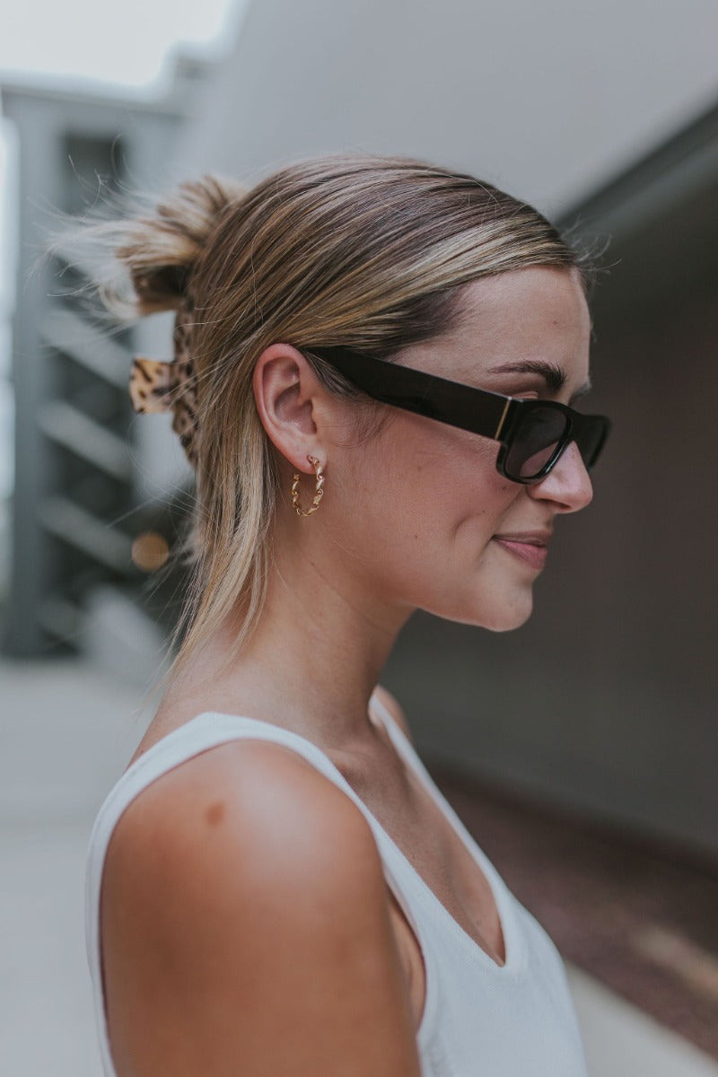 Side view of model wearing the Fresh Start Rope Hoops which features small, open hoops with gold spiral design.