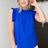 Front view of model wearing the Buena Vista Ruffle Tank that has royal blue fabric, a high neck with ruffle details, and a sleeveless design with pleated ruffle details