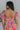 Back view of model wearing the Secret Garden Midi Dress which features purple, red, orange, pink, yellow, green, teal and white fabric, floral print, midi length, flare hem, square neckline, short puff sleeves and smocked back.