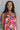 Front view of model wearing the Good Vibes Multi Dress which features orange, red, pink, blue, green and cream fabric, geometric swirl print, pink lining, three-tiered body, ruffle detail, round neckline, tie straps and sleeveless.