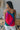 Back view of model wearing the Stuck On You Tank which features red, orange, pink, blue, green and purple pleated fabric, stripe pattern, orange lining, v-neckline, adjustable straps and sleeveless.