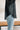 Side view of the Raw Moment Top that features a washed black fabric, a round neckline, a button-up front, a half sleeve, and a raw bottom hem.