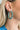 The Lucky Me Earring is a metallic blue, hoop style earring.
