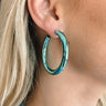 The Lucky Me Earring is a metallic blue, hoop style earring.