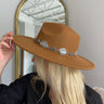 The Blame My Roots Hat is a wide brim hat featuring a camel colored fabric and a silver belt, finished with adjustable ties within for different fits.