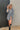 Frontal view of the Falling For You Dress that features a cotton material, an ivory and black plaid print, a collar neckline, a button-up front, a long cuffed sleeve, a front pocket, and a mini length