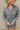 Frontal view of the Falling For You Dress that features a cotton material, an ivory and black plaid print, a collar neckline, a button-up front, a long cuffed sleeve, a front pocket, and a mini length