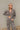 Frontal view of the Still Blooming Top that features a taupe material, a brown floral print, a collar neck, a button-up front, a long cuffed sleeve, and a lettuce edge hem