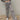 Frontal view of the Still Blooming Pants that features a taupe colored material, a high-rise fit, an elastic waist, adjustable ties at the waist, a lettuce edge hem, and a wide leg fit.
