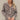 Frontal view of the Still Blooming Top that features a taupe material, a brown floral print, a collar neck, a button-up front, a long cuffed sleeve, and a lettuce edge hem