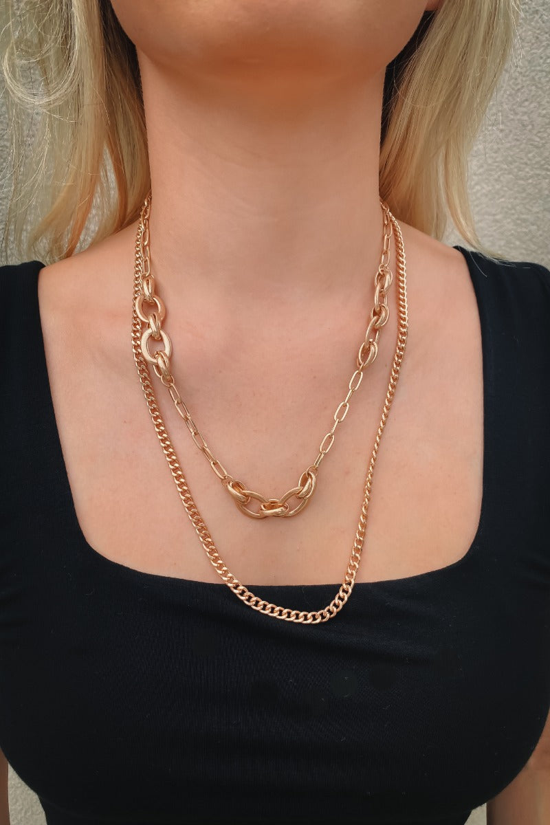 The Everyday Duo Necklace is a double layered necklace, featuring a gold chain and a gold chain link finished with an adjustable link and clasp closure.