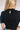 Back view of the Cool and Classy Top that features a black colored material, a round neckline with a lace trim, a half sleeve, a smocked body, a ruffle trim, and a back button closure.