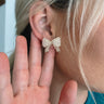 The Down To The Details Earring is a stud style earring featuring a bow shape with clear beading through out.