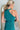 Back view of the Tell Me About It Dress that features a teal ribbed material, a high round neckline, a sleeveless design with one shoulder thick strap, a tight fit, and a mini length.