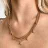 The Meet Me In The Middle Necklace In Natural is a multi-layered necklace featuring natural colored jewel pendants through out finished with a link and clasp closure.