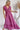 Frontal view of the Living In A Dream Maxi Dress that features a pink colored material, a V neckline, a short ruffle sleeve, a knot detail at the bust, an open back with adjustable tie closures, and a maxi length.