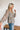 Side view of the Above All Else Top that features a blue colored material with a multi-colored floral print, a V neckline, a long sleeve, a ruched bust, and a flowy fit.