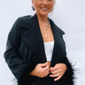 Frontal view of the Always The Optimist Crop Blazer features black fabric, an open front with a collar and lapel, a long sleeve with feather trim, and a cropped fit