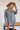 Frontal view of the Falling For You Dress that features a cotton material, an ivory and navy plaid print, a collar neckline, a button-up front, a long cuffed sleeve, a front pocket, and a mini length.
