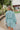 Back view of the Sincerely Yours Dress that features a light teal colored material, a collared V neckline, long cuffed sleeves, a smocked waist, a flowy fit, and a mini length.
