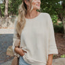 Front view of model wearing the Coast To Coast Sweater, which features a cream knit material with diamond stitching, a scoop neck, an oversized 3/4 sleeve, a thick bottom hem, and an oversized fit.