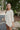 Side view of model wearing the Coast To Coast Sweater, which features a cream knit material with diamond stitching, a scoop neck, an oversized 3/4 sleeve, a thick bottom hem, and an oversized fit.