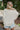 Back view of model wearing the Coast To Coast Sweater, which features a cream knit material with diamond stitching, a scoop neck, an oversized 3/4 sleeve, a thick bottom hem, and an oversized fit.