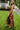 Side view of the What's New Midi Dress that features a copper colored silk material, a black abstract print, a V neckline, a sleeveless design with thin adjustable straps, a side slit, and a midi length.