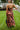 Back view of the What's New Midi Dress that features a copper colored silk material, a black abstract print, a V neckline, a sleeveless design with thin adjustable straps, a side slit, and a midi length.