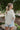 Back view of model wearing the Coast To Coast Sweater, which features a cream knit material with diamond stitching, a scoop neck, an oversized 3/4 sleeve, a thick bottom hem, and an oversized fit.