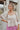 Frontal view of the Mystic Memory Top that features a taupe colored material, a straight neckline, a 3/4 sleeve, an open back with a tie closure, and a flowy fit.