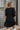 Back view of the Line Of Sight Dress In Black that features a black colored material, a round notched neckline with adjustable ties, long sleeves, vertical ruffle details, and a flowy fit.