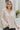 Frontal view of the On To The Next Top that features a champagne satin material, a collar neckline, a long sleeve with feather detailing at the cuff, a button-up front, and a flowy fit.