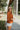 Sideview of model wearing the Forever Young Top in Caramel, which features a caramel colored silky material, a round neckline with a ruffle detail, a notched neckline with adjustable ties, long sleeves, and a flowy fit.