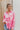 Frontal view of the All Things Lucky Top that features a pink colored material, a collar neckline, a button-up front, a long cuffed sleeve, and a front pocket.