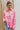 Frontal view of the All Things Lucky Top that features a pink colored material, a collar neckline, a button-up front, a long cuffed sleeve, and a front pocket.