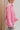 Side view of the All Things Lucky Top that features a pink colored material, a collar neckline, a button-up front, a long cuffed sleeve, and a front pocket.