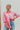Frontal view of the All Things Lucky Top that features a pink colored material, a collar neckline, a button-up front, a long cuffed sleeve, and a front pocket.