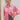 Frontal view of the All Things Lucky Top that features a pink colored material, a collar neckline, a button-up front, a long cuffed sleeve, and a front pocket.