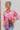 Frontal view of the All Things Lucky Top that features a pink colored material, a collar neckline, a button-up front, a long cuffed sleeve, and a front pocket.